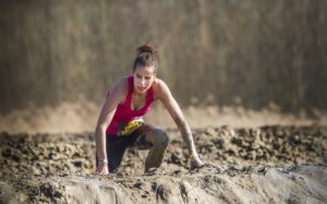 woman deep in mud on obstacle course